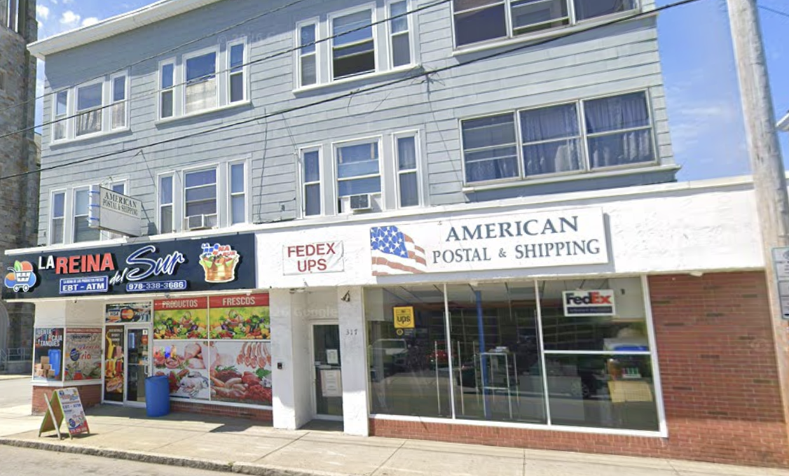 The American Postal & Shipping storefront at 317 South Broadway, with an American flag sign above the windows and FedEx, UPS, and USPS signs beside the entrance
